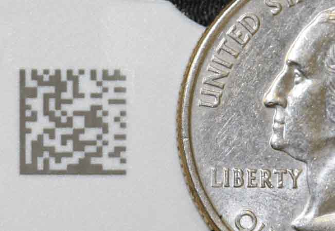 Laser Marking of a small data matrix on white plastic medical device next to a quarter to show the size of the data matrix