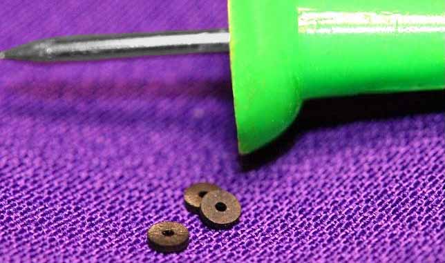 miniature rubber washers next to a green thumb tack