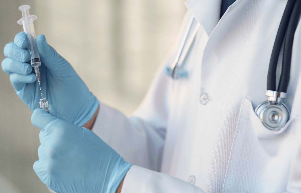 Doctor wearing blue gloves holding a syringe